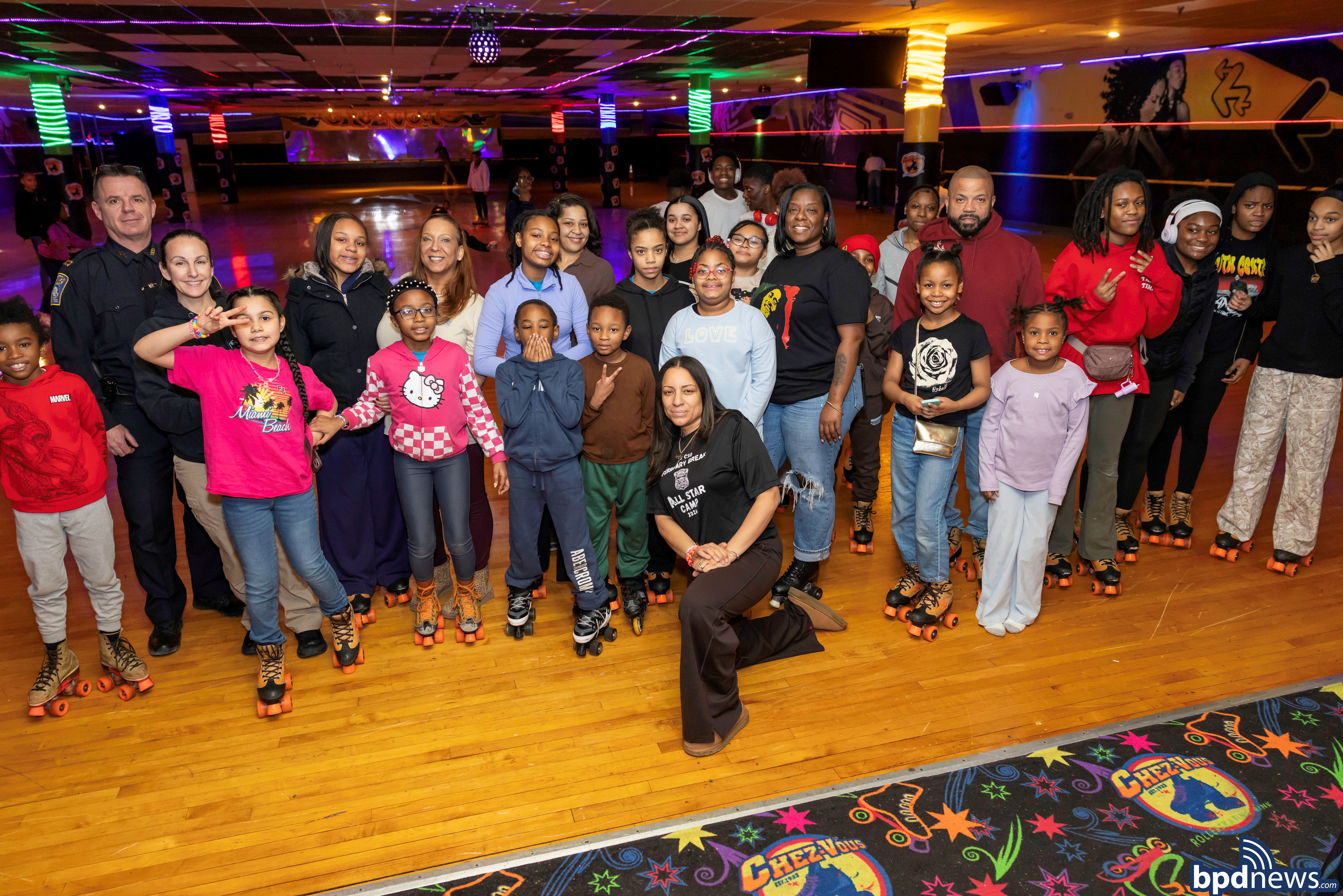 Boston Police Officers Pose for a group photo with community members at Chez Vouz Roller Skating Rink