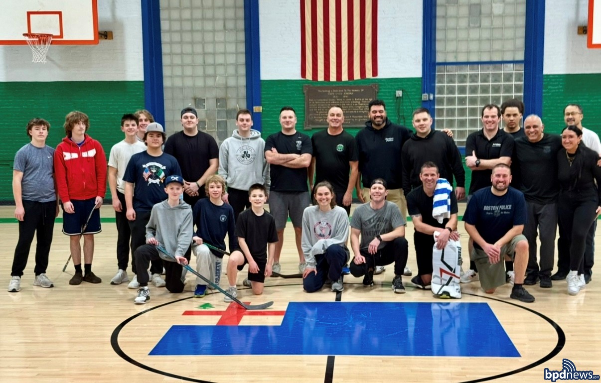 A group photo of BPD officers and community members after the gym hockey game.