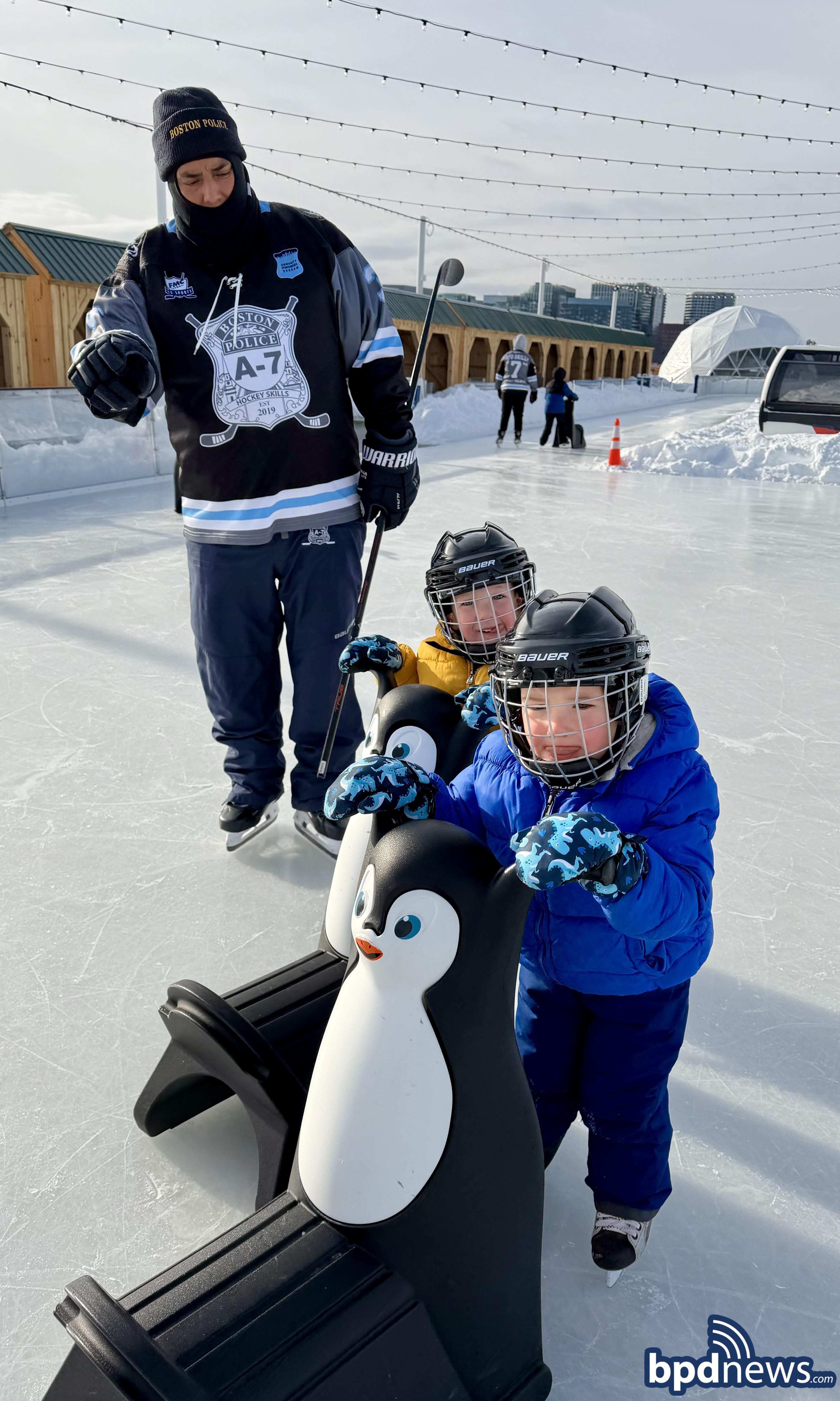 An officer from District A-7 assisting two young community members and showing them tips on how to skate