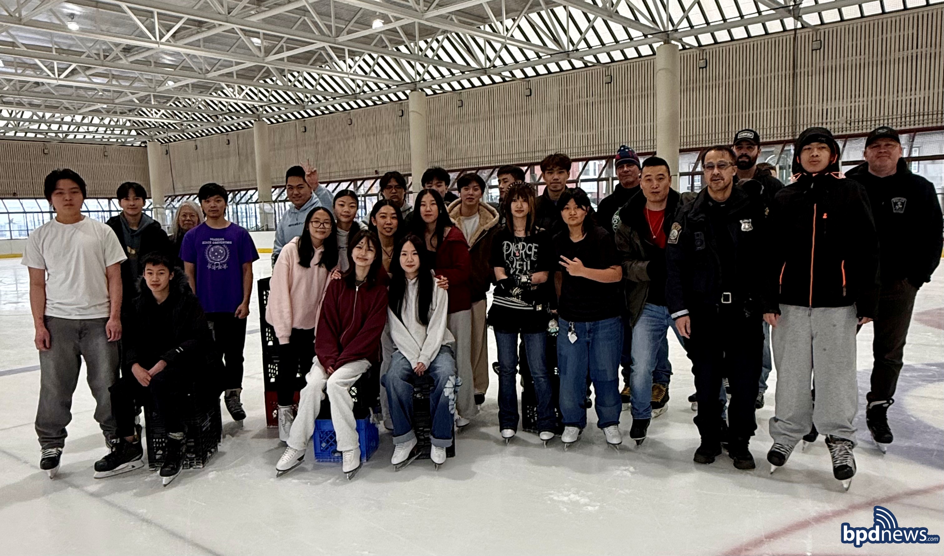 A group picture featuring BPD officers and youth from the Boston Youth Essential Services Program in Chinatown on the ice at Steriti Memorial rink in the North End.