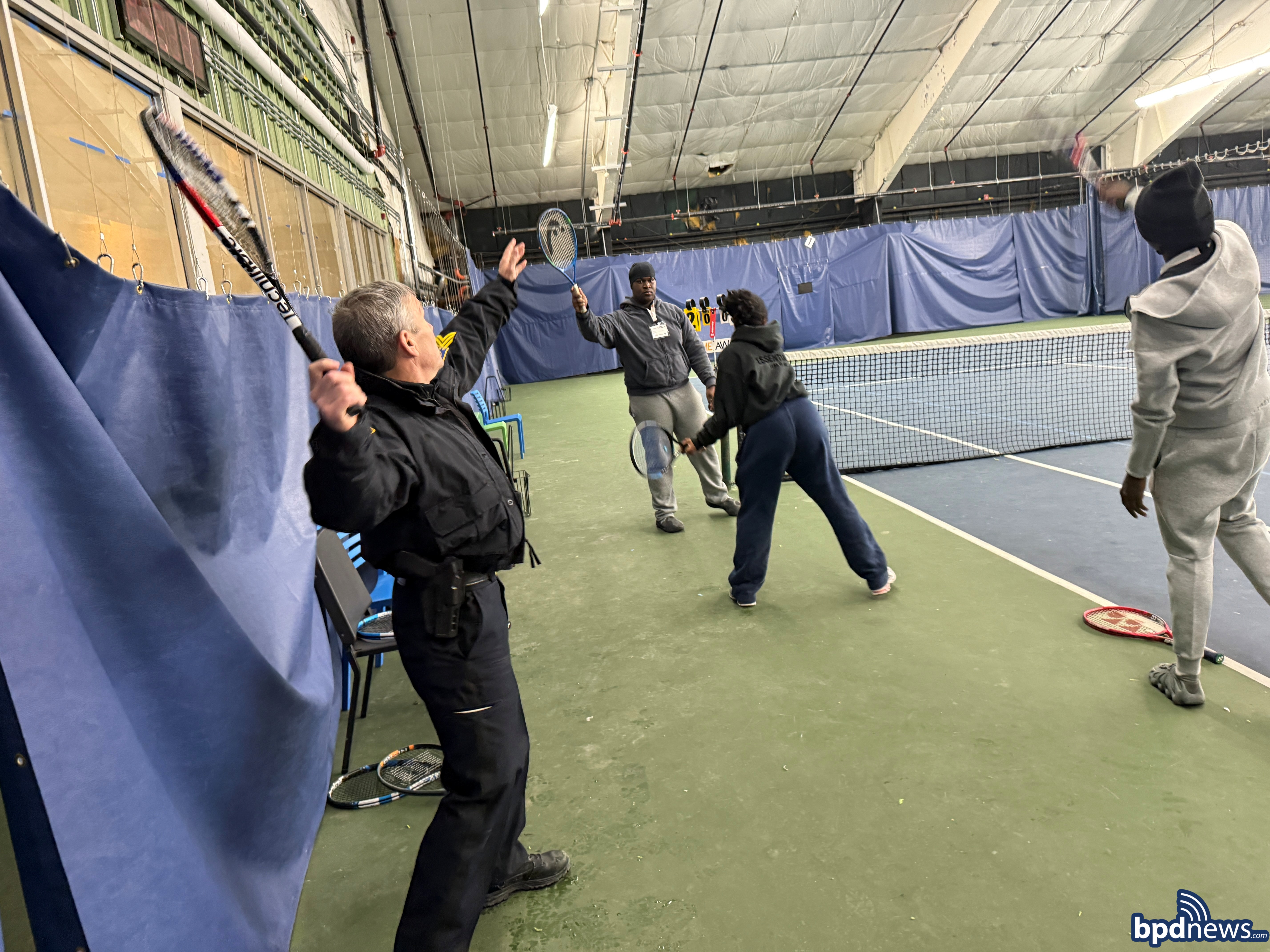 Boston Police Officers and Tennis instructors showing youngsters tennis moves during the Volley Against Violence Program